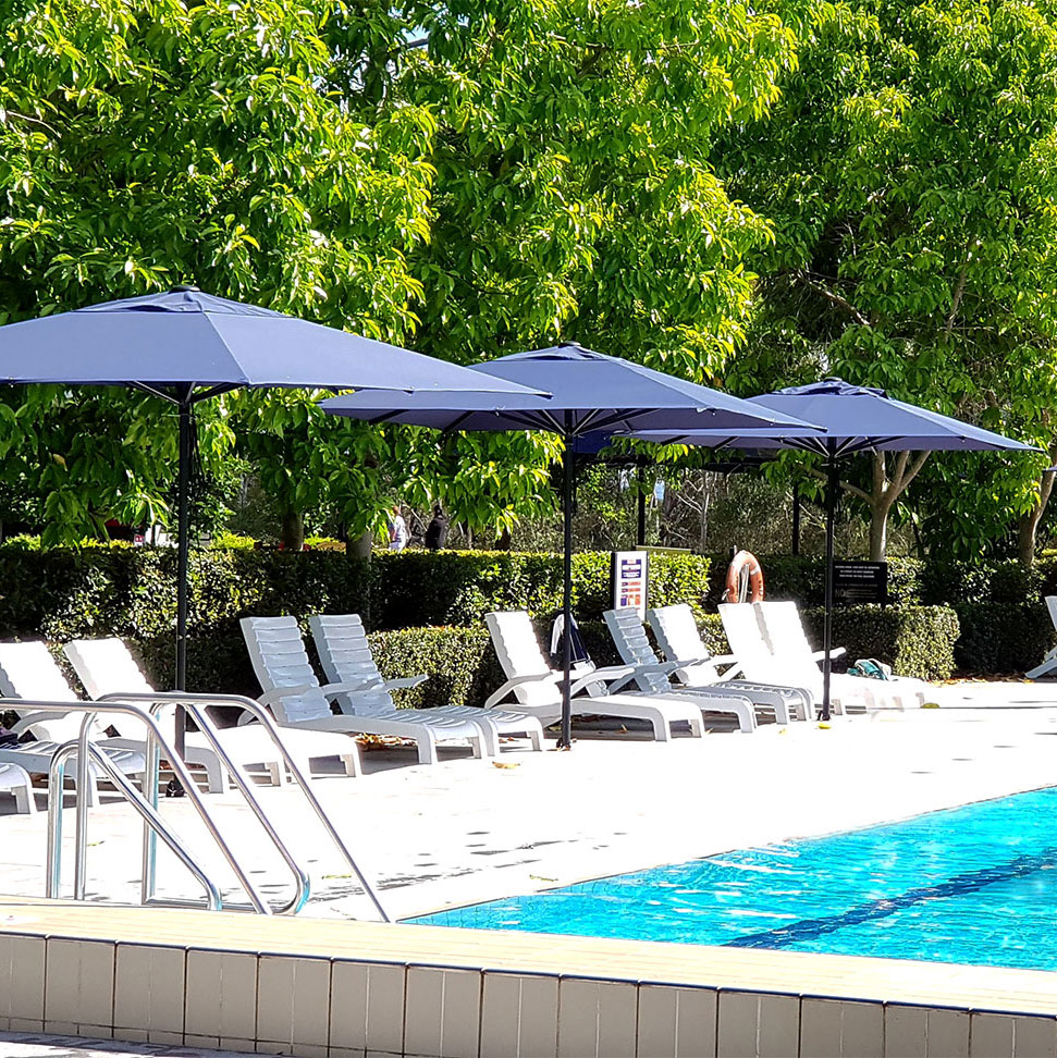 Three Navy Sunranger Cafe Series Commercial Umbrellas near a pool at a hotel